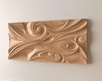May include: A rectangular wooden wall art piece with a carved, swirling design. The light brown wood grain is visible, and the relief carving creates a textured, three-dimensional effect. The artwork is mounted on a neutral-coloured wall.