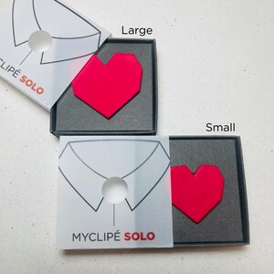 May include: Two boxes, labeled "Large" and "Small", each containing a bright red heart-shaped accessory. The boxes are black with a white overlay featuring a shirt collar design and the text "MYCLIP&Eacute; SOLO".