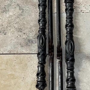 Puede incluir: Juego de herramientas para chimenea negro, que incluye un atizador, una pala y unas pinzas. Las pinzas tienen mangos decorativos con un diseño ovalado. Las herramientas son de metal y están dispuestas sobre una superficie de baldosas claras.