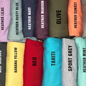 May include: A collection of fabric swatches in various colors, including heather peach, heather purple, deep heather, heather lilac, banana yellow, heather dusty blue, heather navy, red, heather maroon, tahiti, olive, sport grey, heather mint, heather sunset, light pink, and storm.