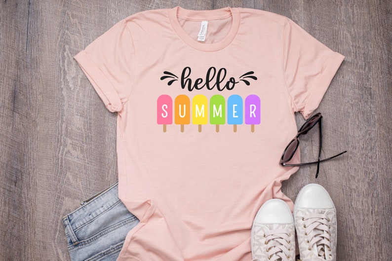 May include: A pink t-shirt with the text "hello summer" in black lettering. The text is surrounded by rainbow popsicle graphics.