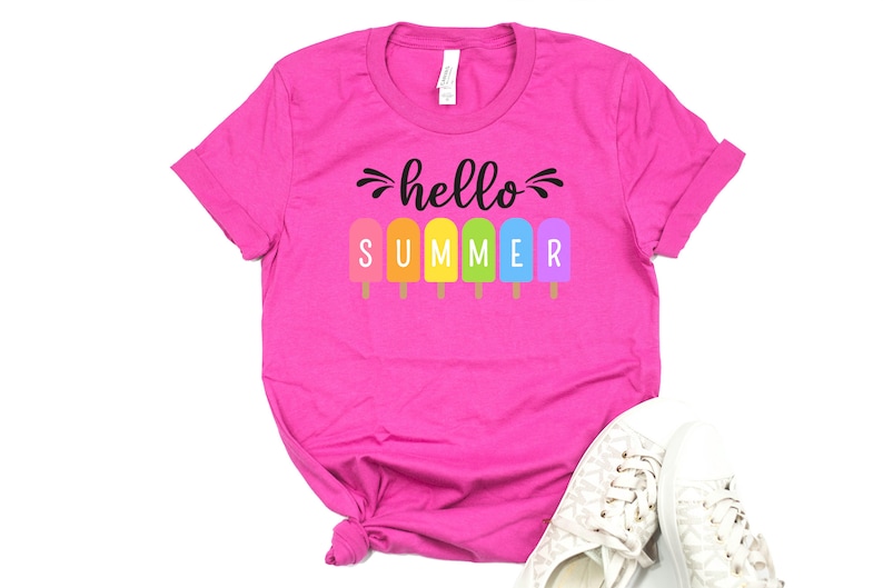 May include: Pink t-shirt with the text "hello summer" in black lettering. The word "summer" is spelled out with colorful popsicle graphics.