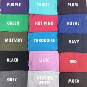 May include: A color chart of 12 different t-shirt colors, including purple, green, military, black, grey, Tahiti, hot pink, turquoise, lilac, heather white, plum, royal, navy, red, and mocha.