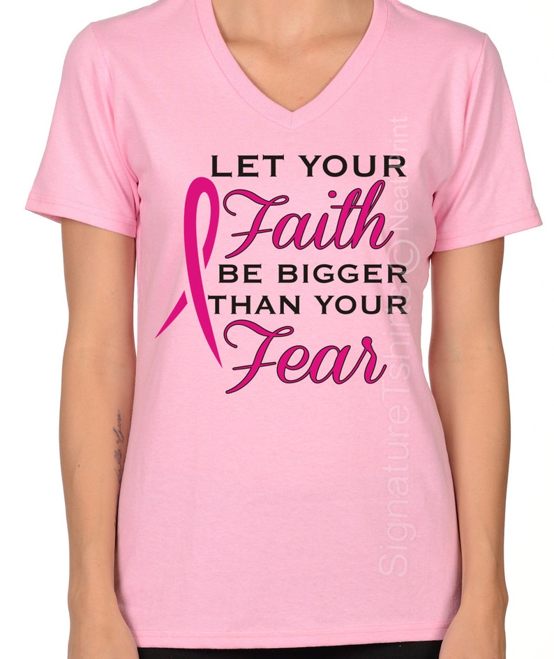 Puede incluir: Camiseta rosa de cuello en V con una cinta rosa y el texto "Deja que tu fe sea m&aacute;s grande que tu miedo".
