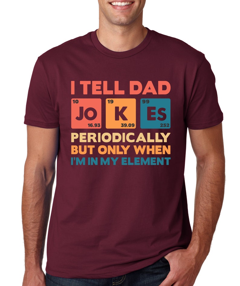 Puede incluir: Camiseta granate con el texto "I TELL DAD JOKES PERIODICALLY BUT ONLY WHEN I'M IN MY ELEMENT" en un dise&ntilde;o colorido de tabla peri&oacute;dica. La camiseta es de cuello redondo.