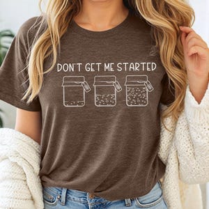 May include: A brown t-shirt with the text "Don't get me started" and a graphic of three jars with labels that say "Nope", "Nope", and "Nope".