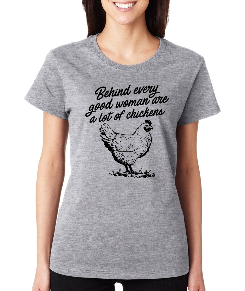 May include: Gray t-shirt with a black graphic that says "Behind every good woman are a lot of chickens" and a black and white illustration of a chicken.