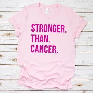 May include: Pink t-shirt with the text "STRONGER. THAN. CANCER." in hot pink.