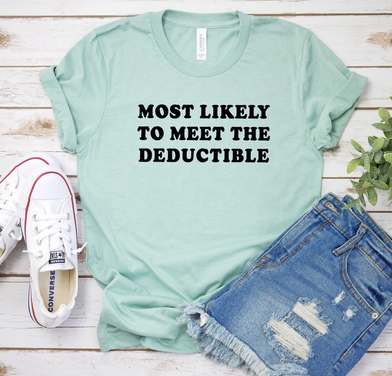 May include: A light green t-shirt with the text "MOST LIKELY TO MEET THE DEDUCTIBLE" in black. The shirt is paired with denim shorts and white sneakers. The shirt is made of a soft material and has rolled-up sleeves.