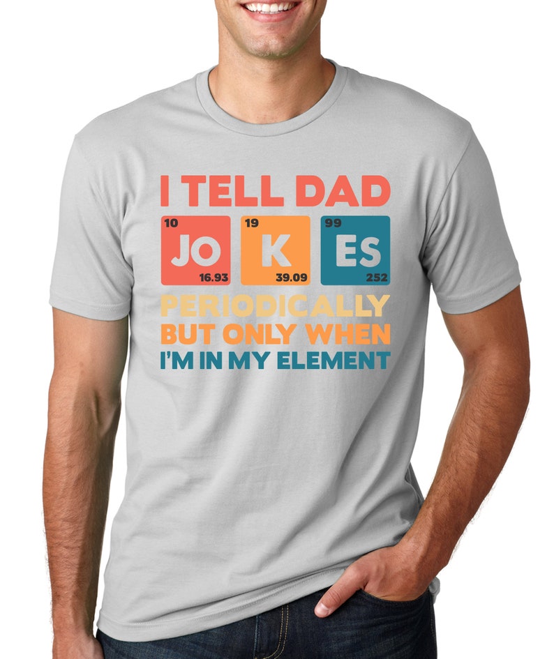 Puede incluir: Una camiseta gris claro con el texto "I TELL DAD JOKES PERIODICALLY BUT ONLY WHEN I'M IN MY ELEMENT" en rojo, naranja y azul. El texto est&aacute; dispuesto en un estilo de tabla peri&oacute;dica.