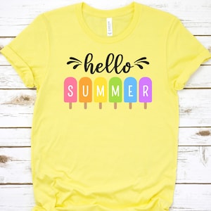 May include: Yellow t-shirt with the text "hello summer" in black lettering. The text is surrounded by rainbow popsicle graphics.