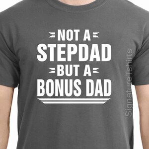 May include: A dark gray t-shirt with white text that reads "Not a Stepdad but a Bonus Dad".