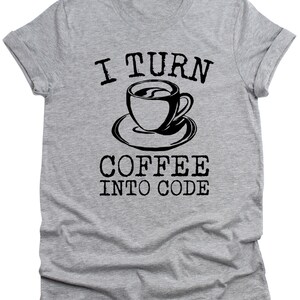 May include: A light gray t-shirt with rolled-up sleeves. The shirt features the text "I TURN COFFEE INTO CODE" in black, with a black coffee cup graphic in the center.