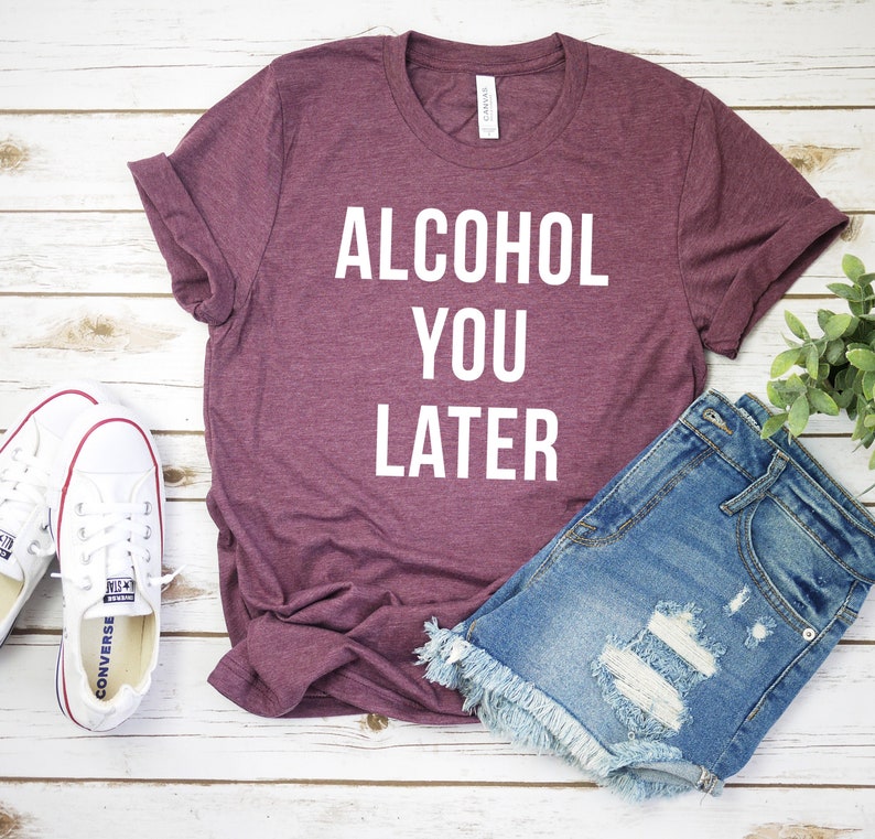 Pu&ograve; includere: Una maglietta color marsala con la scritta "ALCOHOL YOU LATER" in lettere bianche.
