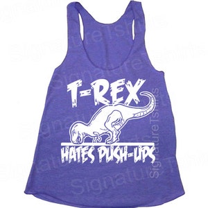 May include: Purple tank top with a white graphic of a T-Rex dinosaur doing a push-up. The text "T-Rex Hates Push-Ups" is printed below the dinosaur.