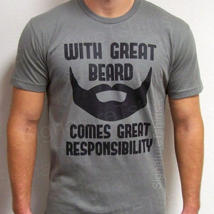 Pode incluir: Uma camiseta cinza com texto preto que diz "With Great Beard Comes Great Responsibility". O texto est&aacute; em negrito, sem serifa. A camiseta apresenta um grande gr&aacute;fico de barba preta.