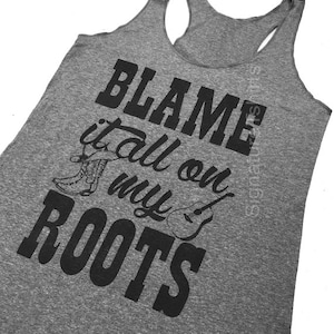 May include: Gray tank top with black text that reads "Blame it all on my roots". The text is accompanied by a graphic of a cowboy boot and a guitar.