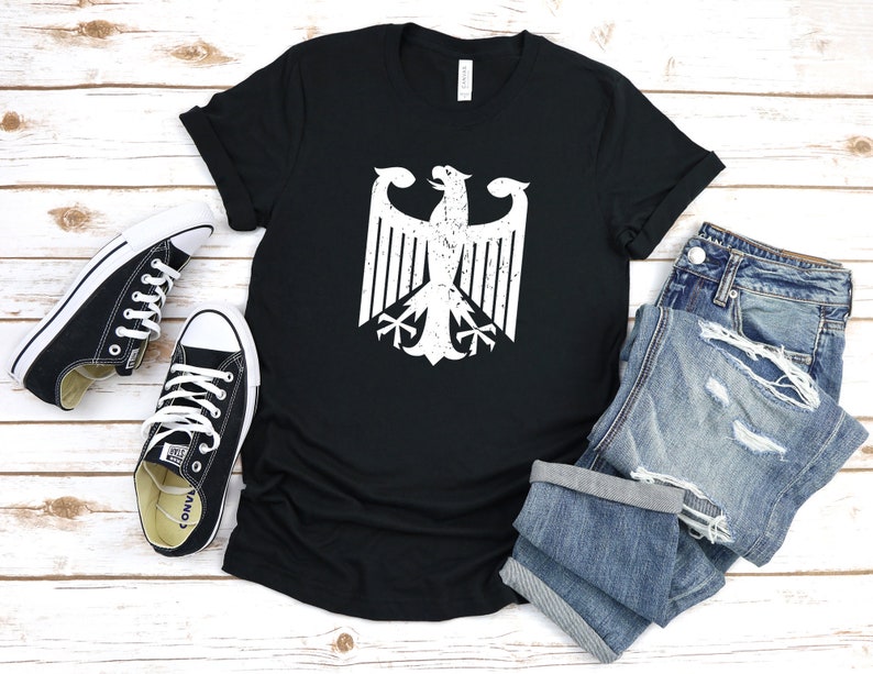 Puede incluir: Camiseta negra con un gr&aacute;fico blanco desgastado del &aacute;guila alemana.