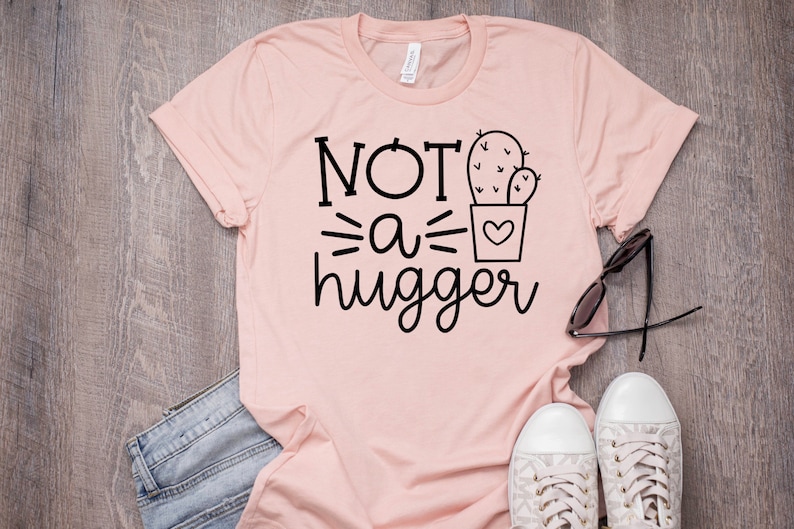 May include: A pink t-shirt with the text "NOT a hugger" and a cactus graphic.