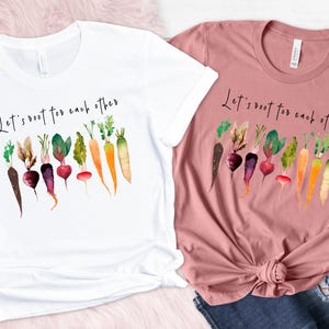 May include: Two t-shirts with the text "Let's root for each other" and a watercolor illustration of various vegetables, including carrots, radishes, and beets.