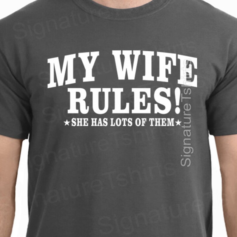 May include: A dark gray t-shirt with white text that reads "My Wife Rules!" and a small star on either side of the text that reads "She has lots of them."