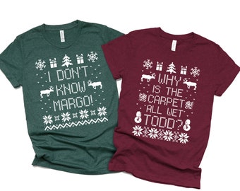 May include: Two Christmas-themed t-shirts with a green and a burgundy color. The green shirt has the text "I don't know Margo!" and the burgundy shirt has the text "Why is the carpet all wet Todd?"