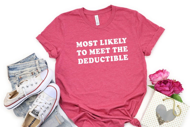 May include: A red t-shirt with the text "MOST LIKELY TO MEET THE DEDUCTIBLE" in white. The shirt is paired with blue jeans, white sneakers, and a gift bag with pink roses. A casual, everyday outfit.