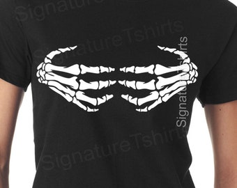 Puede incluir: Camiseta negra con un diseño de mano de esqueleto blanco. Las manos están posicionadas como si estuvieran sosteniendo algo.