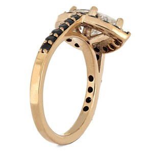 May include: A gold ring with a large clear gemstone surrounded by smaller black gemstones. The ring has a simple band.
