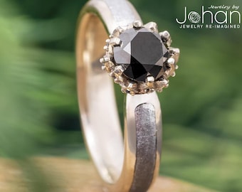 May include: A silver ring with a black diamond set in a silver halo. The ring band has a textured finish.