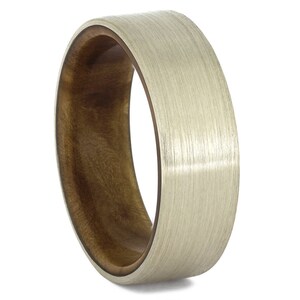 May include: A brushed silver ring with a brown wood inlay. The ring is a simple design with a smooth, polished finish.