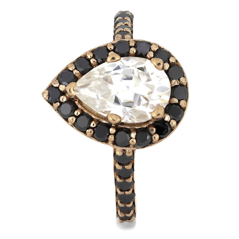 May include: A pear-shaped ring with a large clear stone surrounded by a halo of black stones. The band of the ring is also set with black stones.