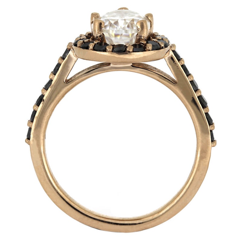 May include: A rose gold ring with a large, clear center stone surrounded by a halo of black stones. The band is also set with black stones.