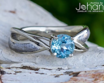 May include: A silver ring with a twisted band and a light blue gemstone. The band has a textured finish.