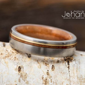 May include: A silver and wood ring with a thin gold band. The ring is made by Johan Jewelry Re-Imagined.