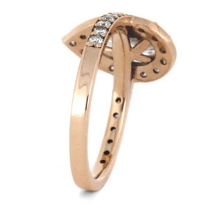 May include: A rose gold ring with a pear-shaped diamond set in a halo of smaller diamonds. The band is also set with smaller diamonds.