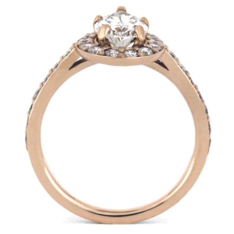 May include: A rose gold engagement ring with a large, round, center diamond surrounded by a halo of smaller diamonds. The band is also set with smaller diamonds.