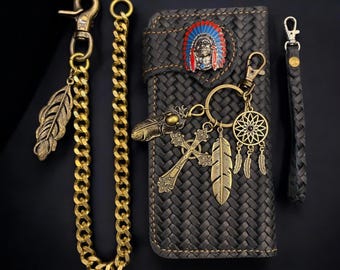 May include: A black leather wallet with a woven pattern and a gold chain attached. The wallet features a Native American headdress design on the front and a dreamcatcher charm attached to the chain. The text "LeathergoodStudio" is visible at the bottom of the image.