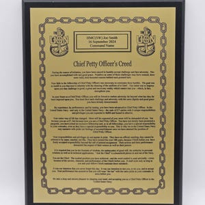 May include: A black plaque with gold text and a gold chain border. The text includes the words "Chief Petty Officer's Creed" and the name "Joe Smith." The plaque commemorates a military achievement.