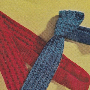 May include: A knitted tie in a deep teal blue color is draped over a red knitted scarf. The tie and scarf are displayed against a yellow background. The knitted texture is visible on both items.