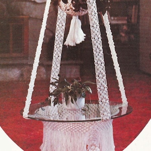 May include: A white macrame hanging plant holder with a glass top, labeled "Glass Slipper" from the book "Macrame Portraits, Book 3, $1.50 by Vickie".