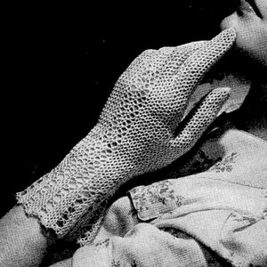 May include: A black and white photo of a woman wearing a crocheted lace glove. The glove is delicate and intricate, with a fine, openwork design. The woman is looking up and to the right, with a thoughtful expression on her face. The photo is from a vintage magazine and includes the text "FAIR LADY No. 2478. See page 20."