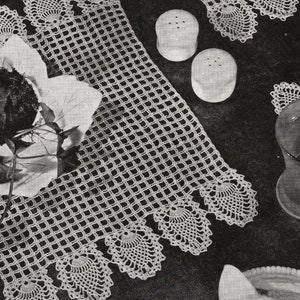 Puede incluir: Dos caminos de mesa de crochet blanco con un borde festoneado y un diseño de piña. Los caminos de mesa están sobre una superficie oscura con un vaso, un plato y saleros y pimenteros.