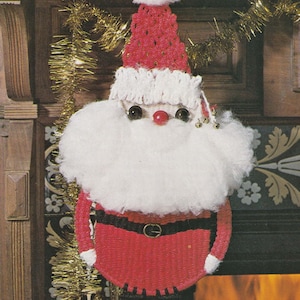 May include: A crocheted Santa Claus ornament with a red hat, white beard, and red suit. The ornament is hanging on a fireplace mantel.