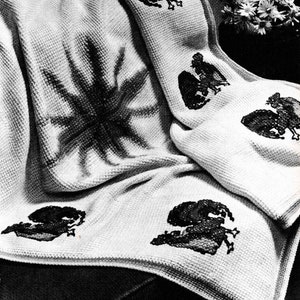 Peut inclure: Une couverture blanche en crochet avec un motif brodé noir d'un oiseau. La couverture est pliée et drapée sur une chaise.