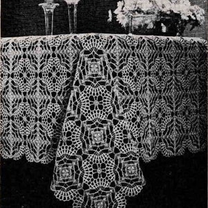May include: A white crocheted tablecloth with a square pattern. The tablecloth is laid out on a table with two candlesticks and a vase of flowers.