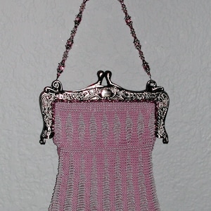 Puede incluir: Un bolso de cuentas rosa con un marco de metal plateado y una correa de cadena de cuentas.
