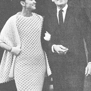 May include: A black and white photo of a couple standing together. The woman is wearing a white crocheted dress and the man is wearing a suit and tie.