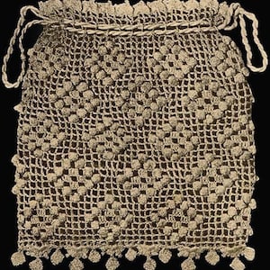 May include: A crocheted drawstring bag in beige with a fringe trim. The bag is made with a repeating pattern of small circles.