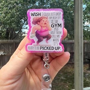 Puede incluir: Un portatarjetas rosa brillante con el texto "WISH I COULD JUST DROP MY BODY OFF AT THE GYM AND HAVE THEM CALL ME WHEN IT'S READY TO BE PICKED UP." La insignia presenta una ilustración de dibujos animados de una mujer con ropa deportiva.